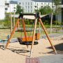 Single Swing (BNS 90cm) playground swing with wooden frame and black circular seat on sandy ground