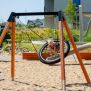 Single Swing (BNS 90cm) with a circular net seat and sturdy wooden frame on a sandy playground.
