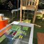 HPL Bench Chess and ludo game with colourful playing pieces on a glass tabletop in outdoor playground setting
